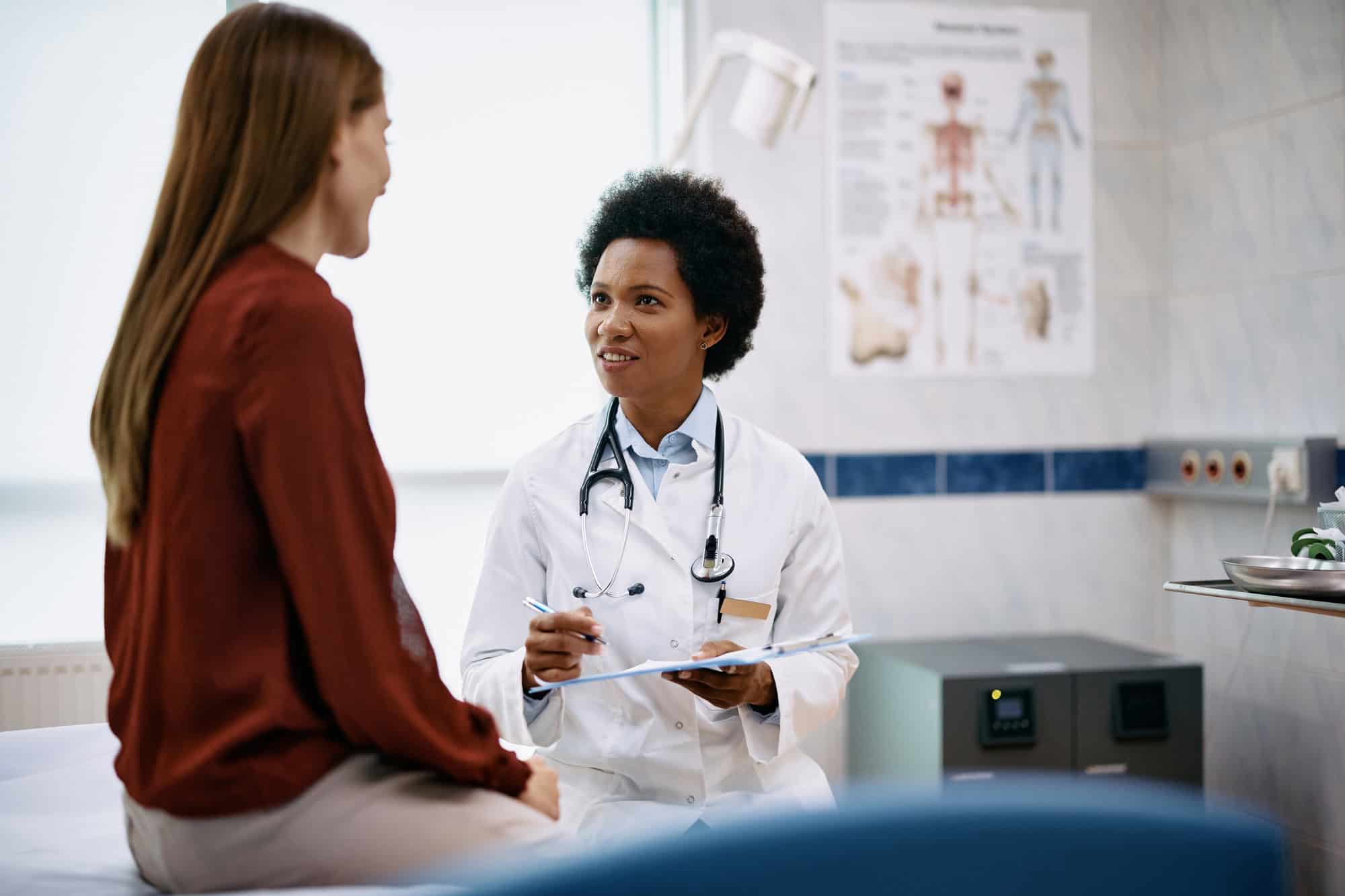 Black female doctor talking to a woman during medical appointment in the hospital.